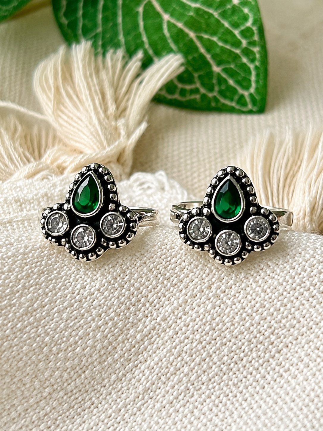925 silver oxidized cluster toe ring pair with green and clear stones on tassel fabric