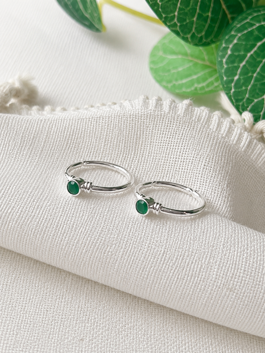  925 silver minimal toe ring pair with small round green stones on white fabric