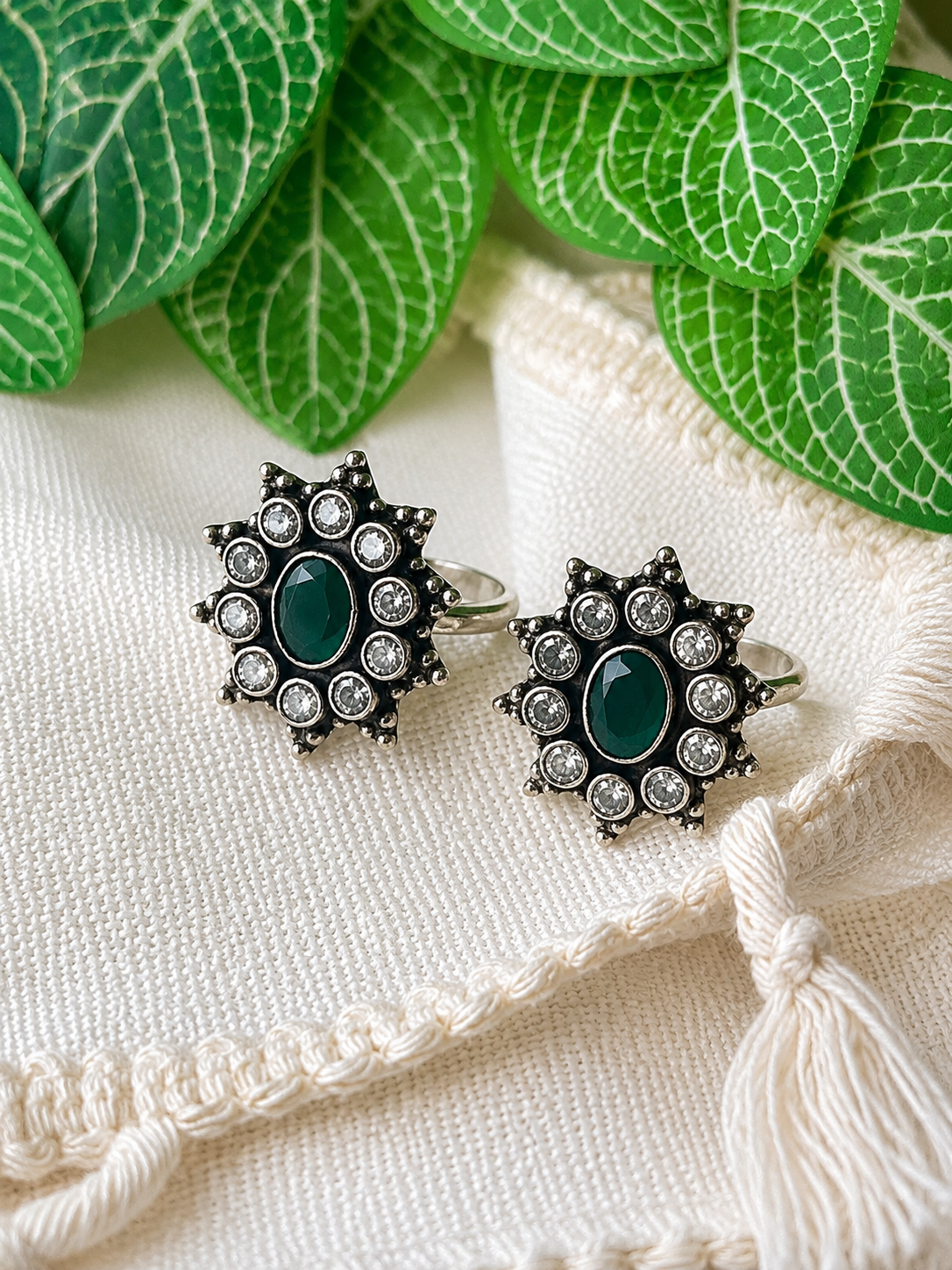 925 silver oxidized flower cluster toe ring pair with green stone on linen fabric with tassel
