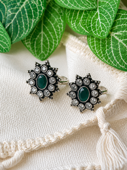 925 silver oxidized flower cluster toe ring pair with green stone on linen fabric with tassel
