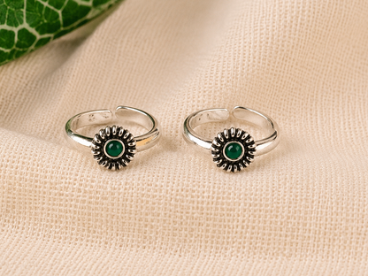 925 silver sunburst toe ring pair with green stone on linen fabric